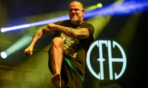 Phil Anselmo z Pantery w Polsce, z mikrofonem w dłoni, na tle sceny z oświetleniem.