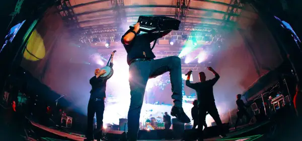 Energetyczny koncert Dropkick Murphys. Muzyk gra na akordeonie, inny na banjo, tłum szaleje.